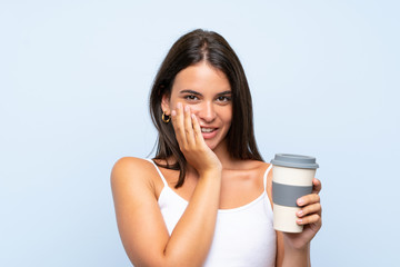 Young woman holding a take away coffee over isolated blue background with surprise facial expression