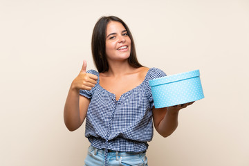Fototapeta premium Young girl over isolated background holding gift box