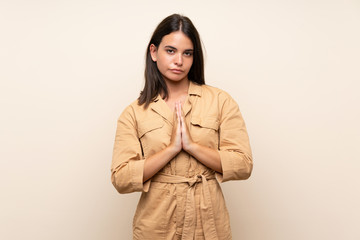 Fototapeta premium Young girl over isolated background keeps palm together. Person asks for something