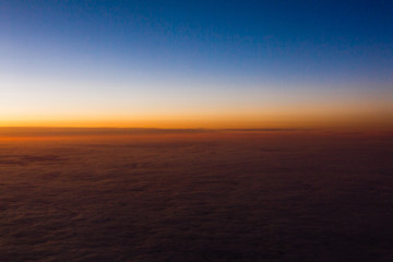 Naklejka na ściany i meble Beautiful sunset sky above clouds with dramatic light. Cabin view from airplane