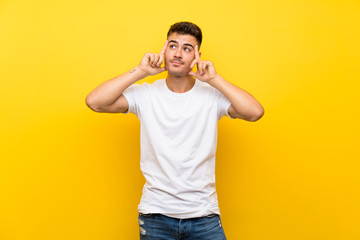 Young handsome man over isolated yellow background having doubts and thinking