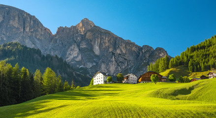 Corvara village, popular tourist alpine village in Dolimite Alps at sunny summer day, Italy