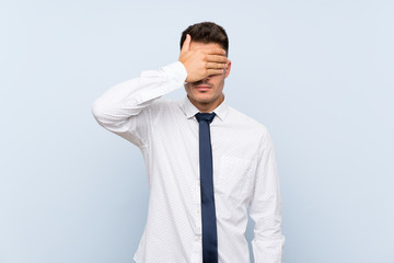Handsome businessman over isolated blue background covering eyes by hands