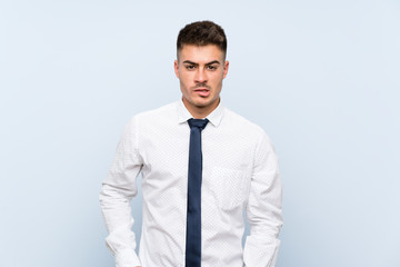 Handsome businessman over isolated blue background having doubts and with confuse face expression