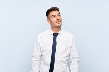 Handsome businessman over isolated blue background laughing and looking up