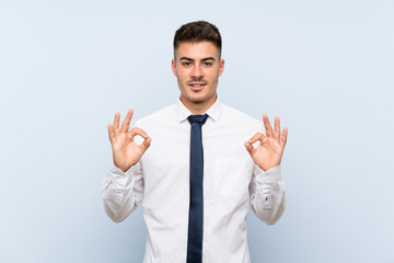 Handsome businessman over isolated blue background showing an ok sign with fingers