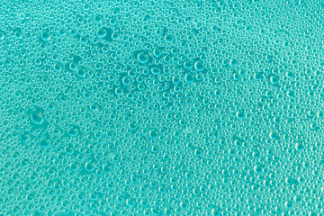Water drops on turquoise surface. Blue and green abstract background of soap bubbles. Aquamarine texture of shiny glass. Drops pattern. Transparent condensation, backdrop. Modern design.