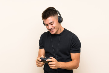 Young handsome man playing with a video game controller over isolated background