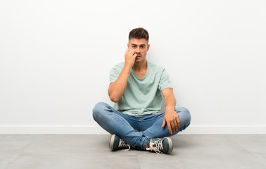 Young handsome man sitting on the floor nervous and scared