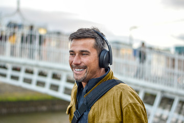 Obraz premium Spanish young man tourist in Dublin city with black headphones and leather jacket.
