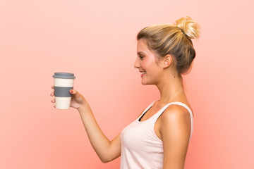 Young blonde woman holding a take away coffee with happy expression