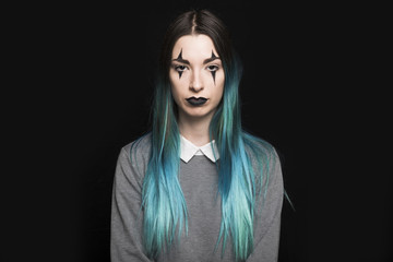 Young woman with blue hair and makeup standing in studio
