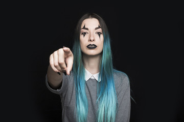 Young woman with blue hair and dark make up posing in studio
