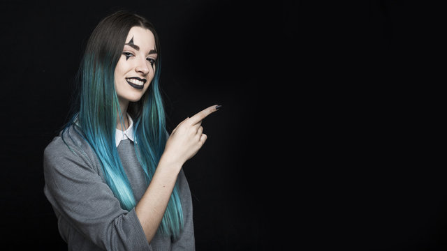 Young blue haired woman pointing with finger aside