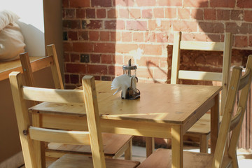 Interior of a small cafe, wooden table and chairs, sugar bowl and napkins