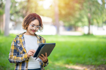 Happy woman using and looking at her digital tablet outdoors, Woman in shirt using digital tablet outdoors