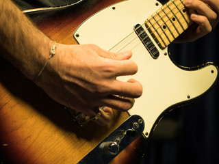 Closeup of man playing sunburst finish electric guitar