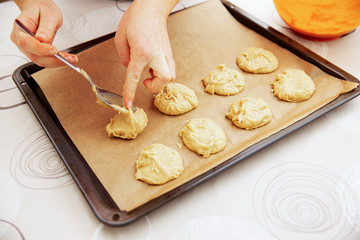 Female hands spread the cookie dough on a baking sheet covered with baking paper.
