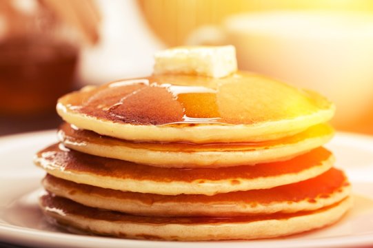 Panckes with butter and syrup with coffee in the background