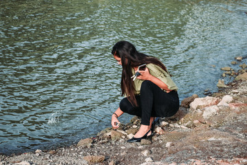 Indian girl with long hair throwing pebbles in water at lake. Nyari dam, Rajkot, India.