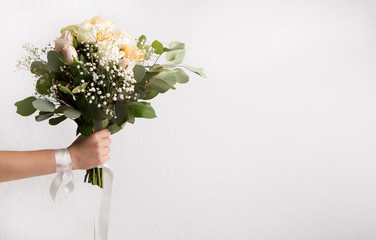 Bridesmaid holding wedding bouquet of roses on white
