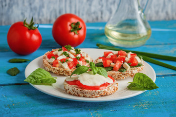 healthy sandwiches  rice  cakes with mozzarella tomatoes basil and chopped vegetables on plate on the blue table
