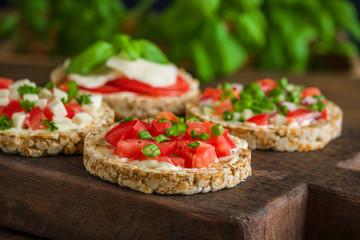 healthy snacks with rice  cakes  diced tomatoes mozzarella cheese spinach basil   on cutting board close up
