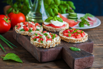open sandwiches with rice  cakes  diced tomatoes mozzarella cheese spinach basil   on cutting board close up