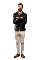 Fototapeta premium Handsome man with beard holding copyspace imaginary on the palm to insert an ad over isolated white background