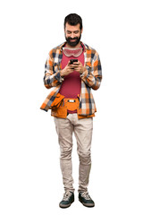 Craftsmen man sending a message with the mobile over isolated white background
