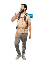 Hiker man yawning and covering wide open mouth with hand over isolated white background