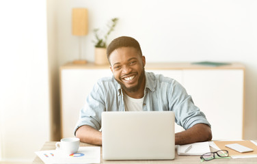 Positive black freelancer posing to camera and laughing