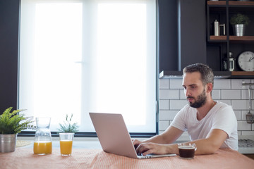 Focused young man working on small business start up with a laptop.