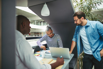 Diverse businessmen working in an office pod together