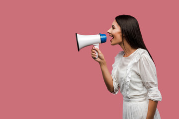 side view of woman screaming in megaphone isolated on pink