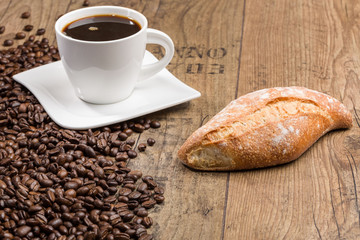 Bakery products and cup of coffee and coffee beans on a wooden table