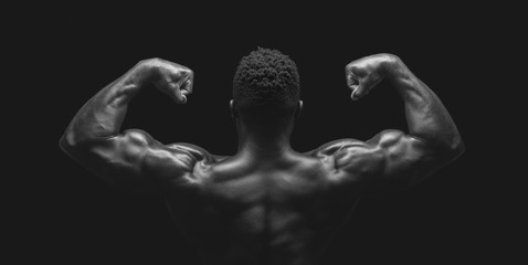 African athlete demonstrating double biceps pose over black studio background