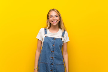 Blonde young woman over isolated yellow background with glasses