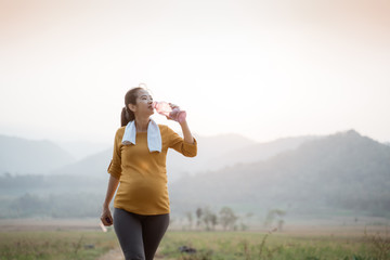 thirsty pregnant woman after workout drinking a bottle of water