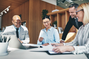 Laughing businesspeople going over paperwork together during an