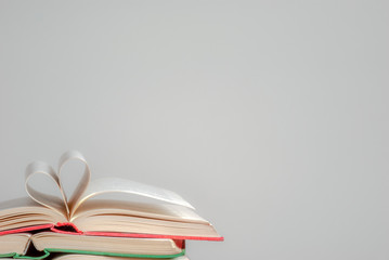 Old books on a light background. The pages of the book are folded in the shape of a heart. copys space