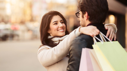 Loving woman embracing husband after shopping, free space