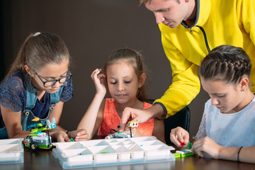 Obraz premium Kids creating robots with teacher. Early development, diy, innovation, modern technology concept.