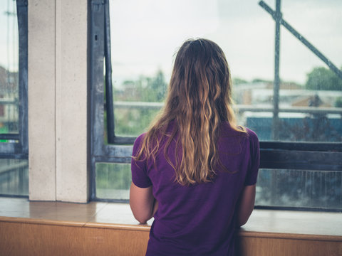 Young woman looking out the window of city apartment