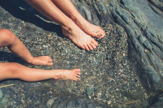 Feet of young woman and toddler in rock pool