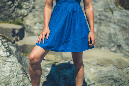 Young woman in blue dress standing on rocks