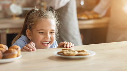 Adorable little girl looking at cookies with desire