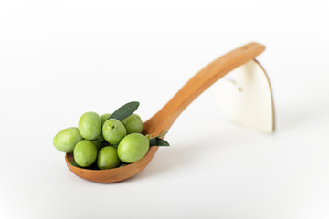 Olive verdi e foglie d'ulivo in un cucchiaio in legno
