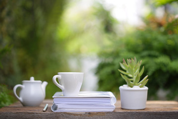 tea cup and tea pot with small plant pot and diary notebook on wooden table