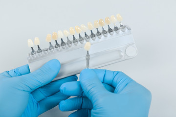 dentist hand with shade guide to check veneer of teeth for bleaching